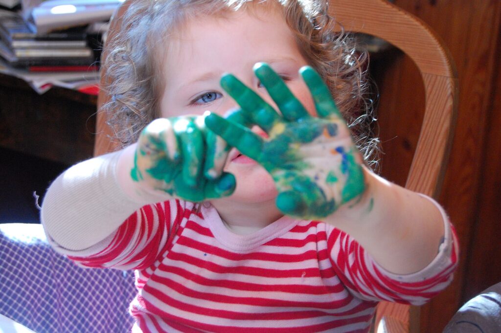Child fingerpainting - This file is licensed under the Creative Commons Attribution 2.0 Generic license - Source https://commons.wikimedia.org/wiki/File:Paint_on_hands.jpg